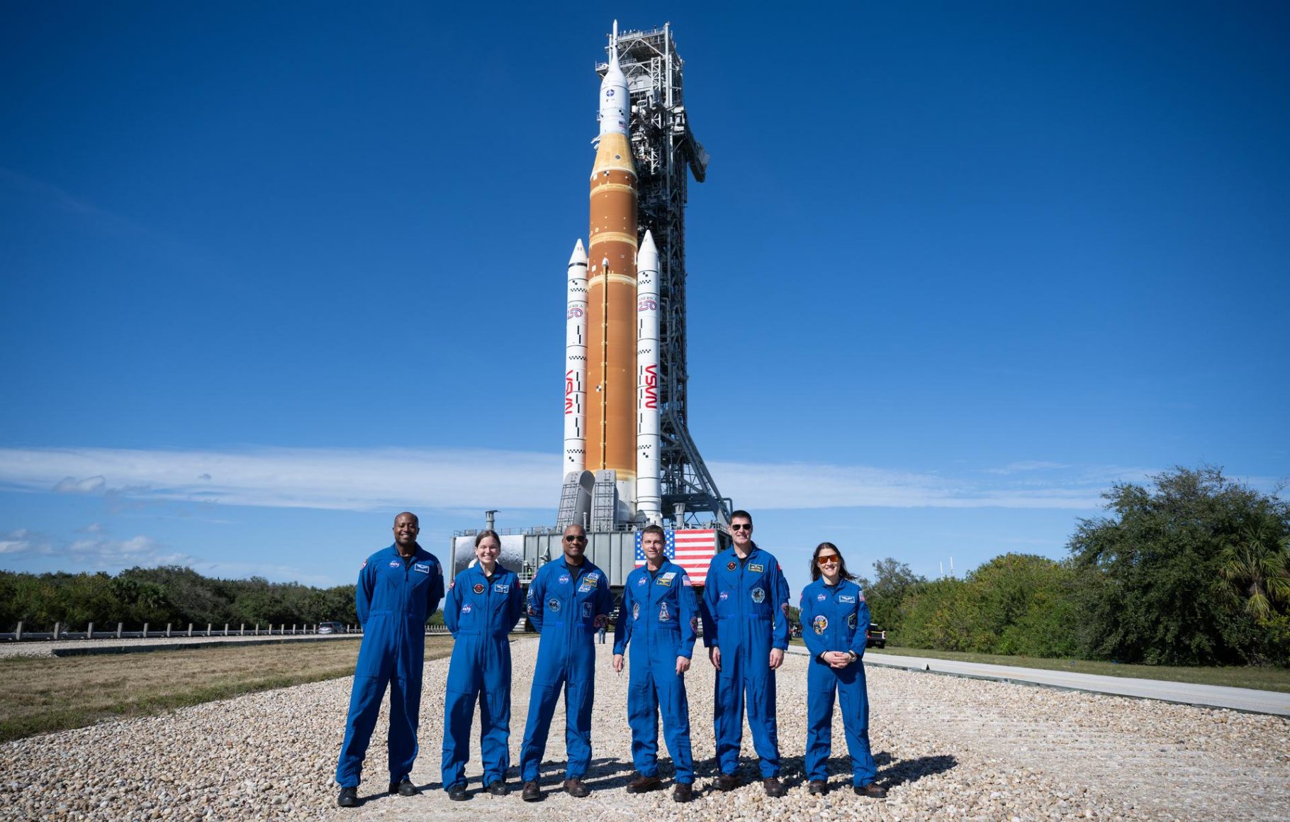 Astronauts posing in front of the Artemis II rocket on its launcher